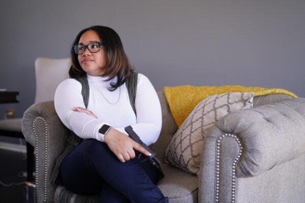 Cierra Hayes holds her first gun on her living room couch in Richton Park, Ill., on March 13, 2022. (Cara Ding/The Epoch Times)