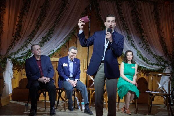 Caleb Max, the youngest Republican congressional candidate for the 10th District of Virginia, holds a copy of the U.S. Constitution as other candidates looked on. (L to R) David Beckwith, Mike Clancy, and Brooke Taylor. (Terri Wu/The Epoch Times)