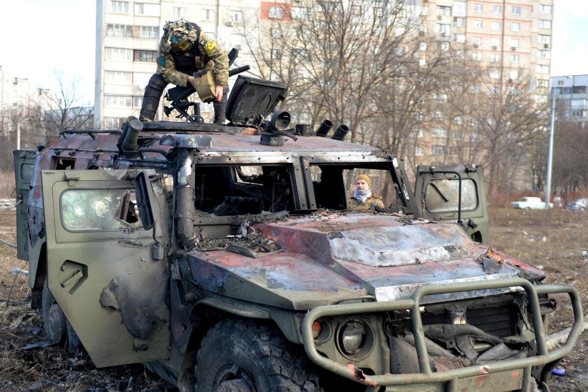 A Ukrainian Territorial Defence fighter examines a destroyed Russian infantry mobility vehicle after a fight in Kharkiv, Ukraine, on Feb. 27, 2022. (Sergey Bobok/AFP/Getty Images)