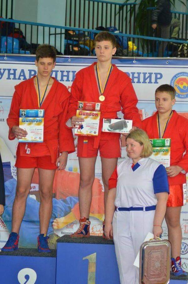 Artem Pryimenko (center) stands atop a podium after winning a sambo wrestling competition. (Courtesy Anna Pryimenko)
