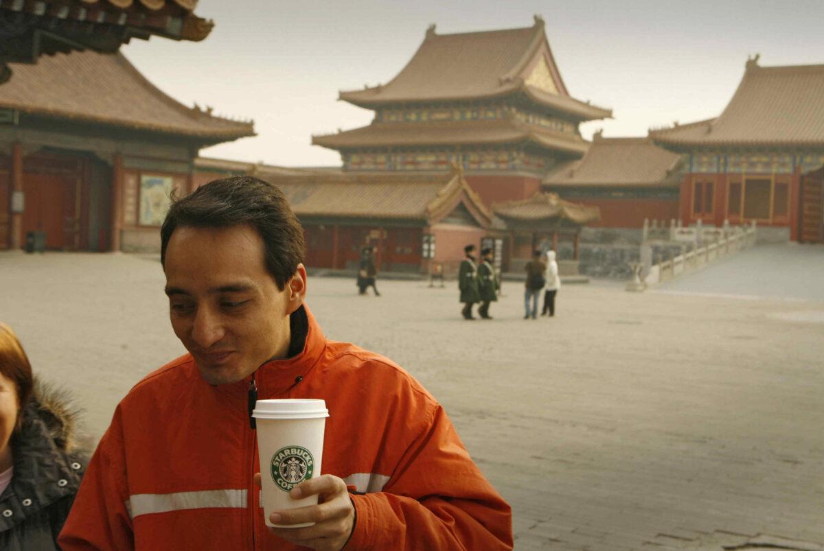 A tourist carries a coffee outside the Starbucks coffeehouse in Beijing's Forbidden City on Jan. 19, 2007. (Peter Parks/AFP via Getty Images)