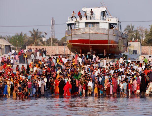 People gather at the bank of Shitalakshya river, where a ferry has sunk after colliding with a sand carrier ship in Narayanganj, Bangladesh, on March 20, 2022. (Mohammad Ponir Hossain/Reuters)