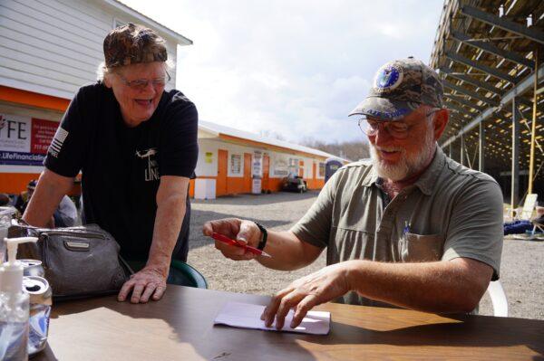 Trucker Ron Coleman signs his autograph for a supporter at Hagerstown Speedway in Hagerstown, Md., on Mar. 19, 2022. (Terri Wu/The Epoch Times)