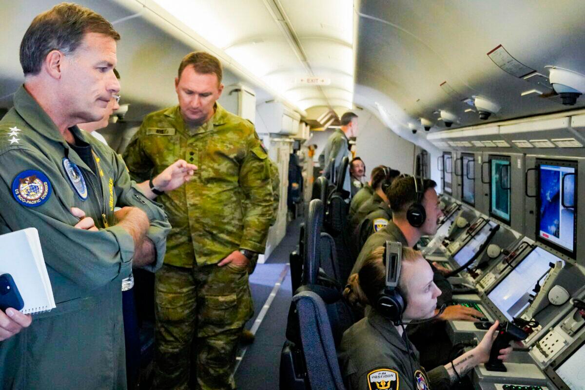 Admiral John C. Aquilino (L), Commander of the U.S. Indo-Pacific Command (INDOPACOM), looks at videos of Chinese structures and buildings on board a U.S. P-8A Poseidon reconnaissance plane flying at the Spratlys group of islands in the South China Sea, on March 20, 2022. (Aaron Favila/AP Photo)