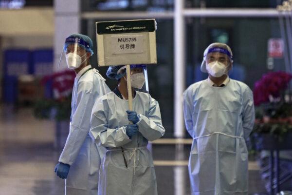 A worker from the China Eastern holds a signboard waiting to lead relatives of the victims aboard China Eastern's flight MU5735 to a cordoned off area, in Guangzhou Baiyun International Airport in Guangzhou, capital of south China's Guangdong Province, on March 21, 2022. (Chinatopix Via AP)