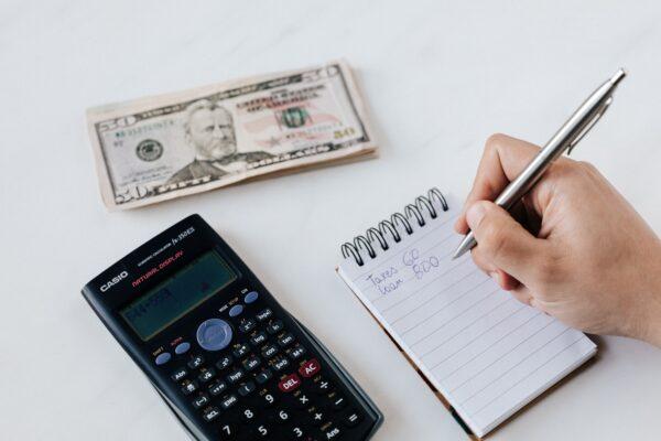 Stock photo of a financial planner writing on a notebook. (Karolina Grabowska/Pexels)