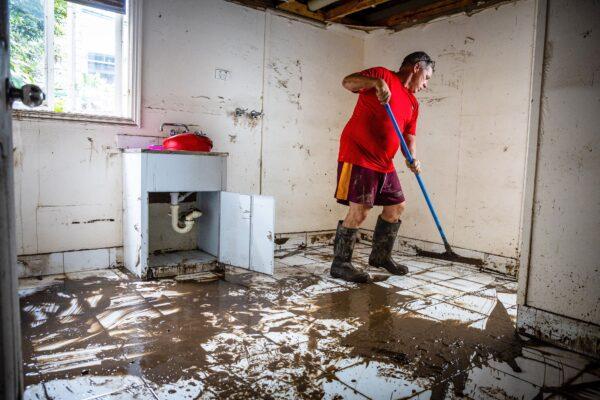 A man clears mud from the lower level of a home following flooding in the suburb of Newmarket in Brisbane, Australia, on March 1, 2022. (Patrick Hamilton/AFP via Getty Images)