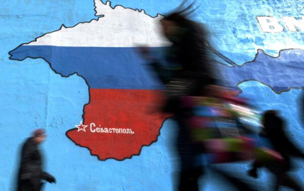 Pedestrians walk past a wall painting depicting a map of the Crimean peninsula bearing the colors of Russia's national flag in Moscow, Russia, on March 31, 2014. (Vasily Maximov/AFP via Getty Images)