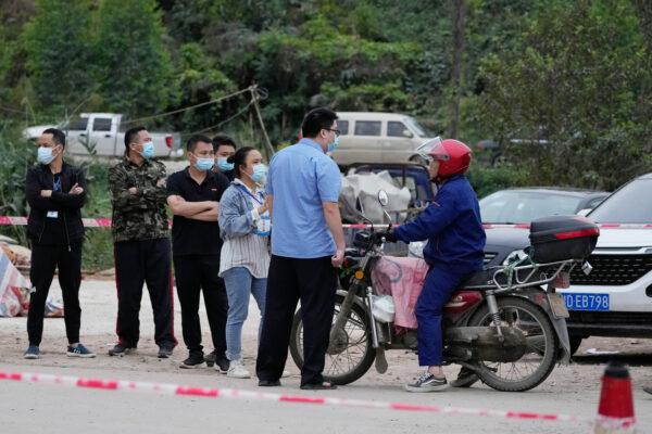 Workers control access at the entrance to the village which leads to the site of the China Eastern plane crash in southwestern China's Guangxi province on March 22, 2022. (Ng Han Guan/AP Photo)