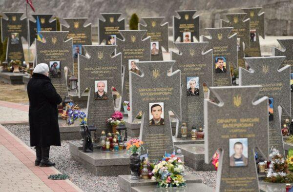 A woman stands in front of graves of Ukrainian soldiers during commemoration ceremony at the Lychakiv Cemetery in Lviv, western Ukraine, on Feb. 20, 2022. (Yuriy Dyachyshyn/AFP via Getty Images)