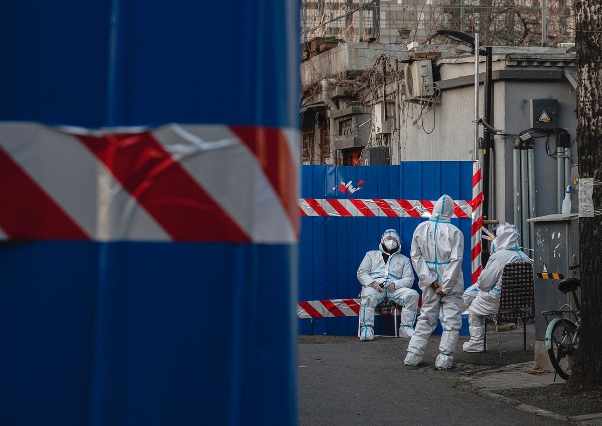 Guards wear protective suits as they watch over a barricaded community that was locked down for health monitoring after recent cases of COVID-19 were found in the area in Beijing, China, on March 21, 2022. (Kevin Frayer/Getty Images)