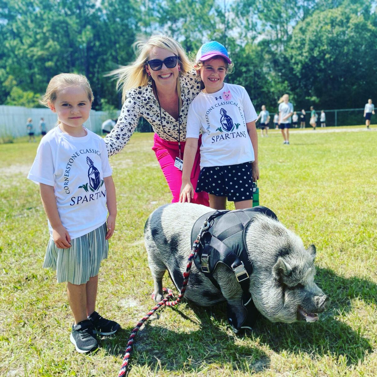 Lindsey Hoyt with her two daughters. Cornerstone Classical Academy second graders had just finished reading Charlotte's Web, so they brought a pig to campus to celebrate their accomplishment. (Courtesy of Lindsey Hoyt)