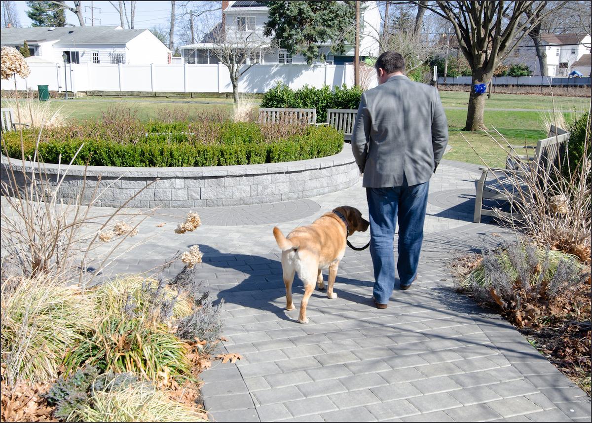 Conor McDonald walks his mother’s dog, Murphy, in the Steven McDonald Garden of Forgiveness in Malverne, N.Y., where he often goes for quiet contemplation. (Dave Paone/The Epoch Times)
