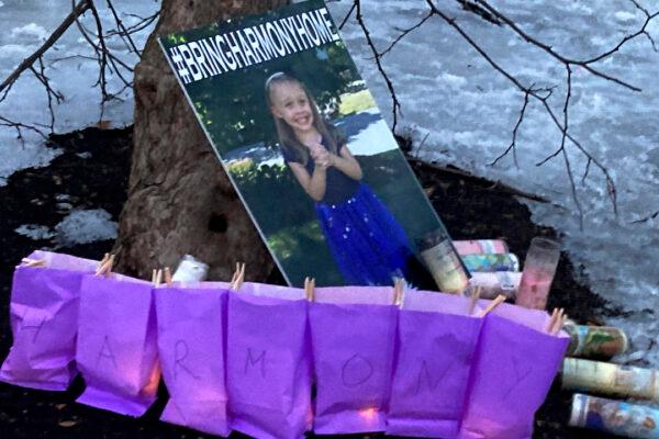 A poster of Harmony Montgomery, who has been missing since 2019, rests against a tree during a candlelight vigil at Bass Island Park in Manchester, N.H., on Feb. 12, 2022. (Kathy McCormack/AP Photo)