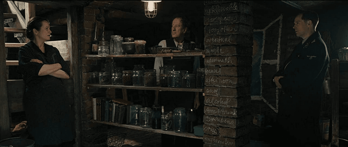 (L–R) Rosa Hubermann (Emily Watson), Hans Hubermann (Geoffrey Rush), and Gestapo agent (Sebastian Hülk), in the Hubermanns' basement, in "The Book Thief." (20th Century Fox)