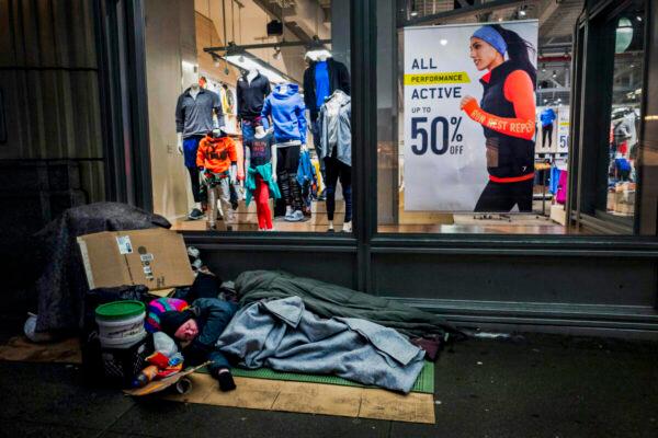 A homeless person sleeps under a blanket outside an Old Navy store window display in New York, on Jan. 11, 2017. (Mark Lennihan/AP Photo)