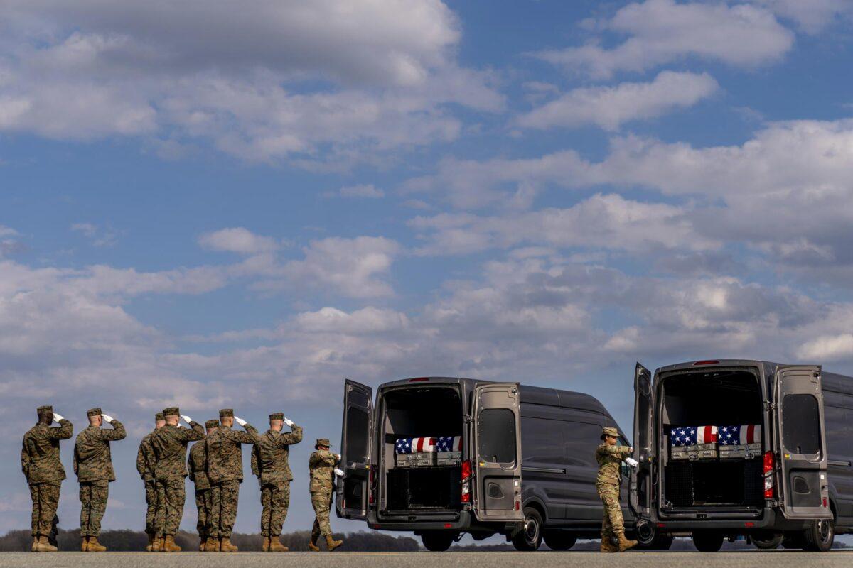 A U.S. Marine Corps carry team salutes transfer cases containing the remains of from left, Cpl. Jacob M. Moore of Catlettsburg, Ky., Gunnery Sgt. James W. Speedy of Cambridge, Ohio, Capt. Ross A. Reynolds of Leominster, Mass., and Capt. Matthew J. Tomkiewicz of Allen, Ind., as they are loaded into transfer vehicles during a casualty return at Dover Air Force Base on March 25, 2022. (Andrew Harnik/AP Photo)