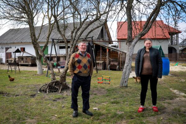Roman Login (L) and his daughter Oksana Salabai stand in their front yard in Koty, Ukraine, on March 25, 2022. (Charlotte Cuthbertson/The Epoch Times)