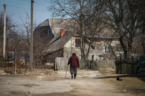 An elderly woman walks through the village of Koty, Ukraine, on March 25, 2022. (Charlotte Cuthbertson/The Epoch Times)