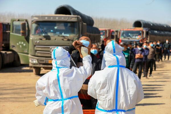 Stranded lorry drivers line up for nucleic acid testing at a parking lot, following a lockdown in Tangshan city, Hebei province, China on March 26, 2022. (China Daily via Reuters)