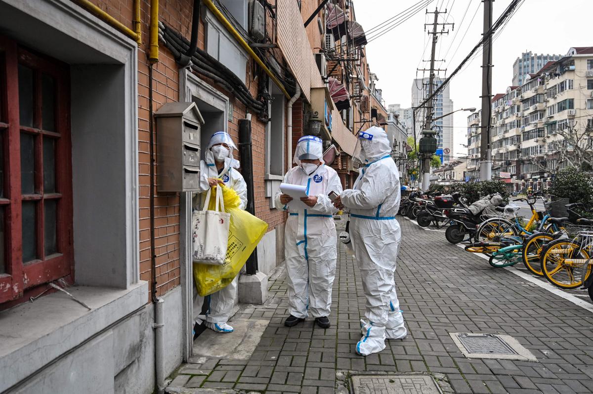 Health workers wearing protective gear as a measure against the COVID-19 coronavirus work along a street in Jing'an district in Shanghai on March 26, 2022. (Hector Retamal/AFP via Getty Images)
