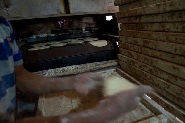 A baker prepares Egyptian traditional flatbread at a bakery in Cairo on March 2, 2022. The Russian tanks and missiles attacking Ukraine are also threatening the food supply and livelihoods of people in Europe, Africa, and Asia who rely on the vast, fertile farmlands of the Black Sea region. (Nariman El-Mofty/AP Photo)