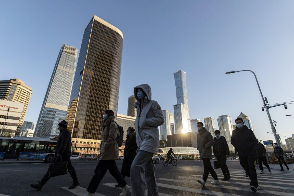 Pedestrians cross a road in front of buildings in the central business district in Beijing, China, on Nov. 23, 2021. (Qilai Shen/Bloomberg via Getty Images)