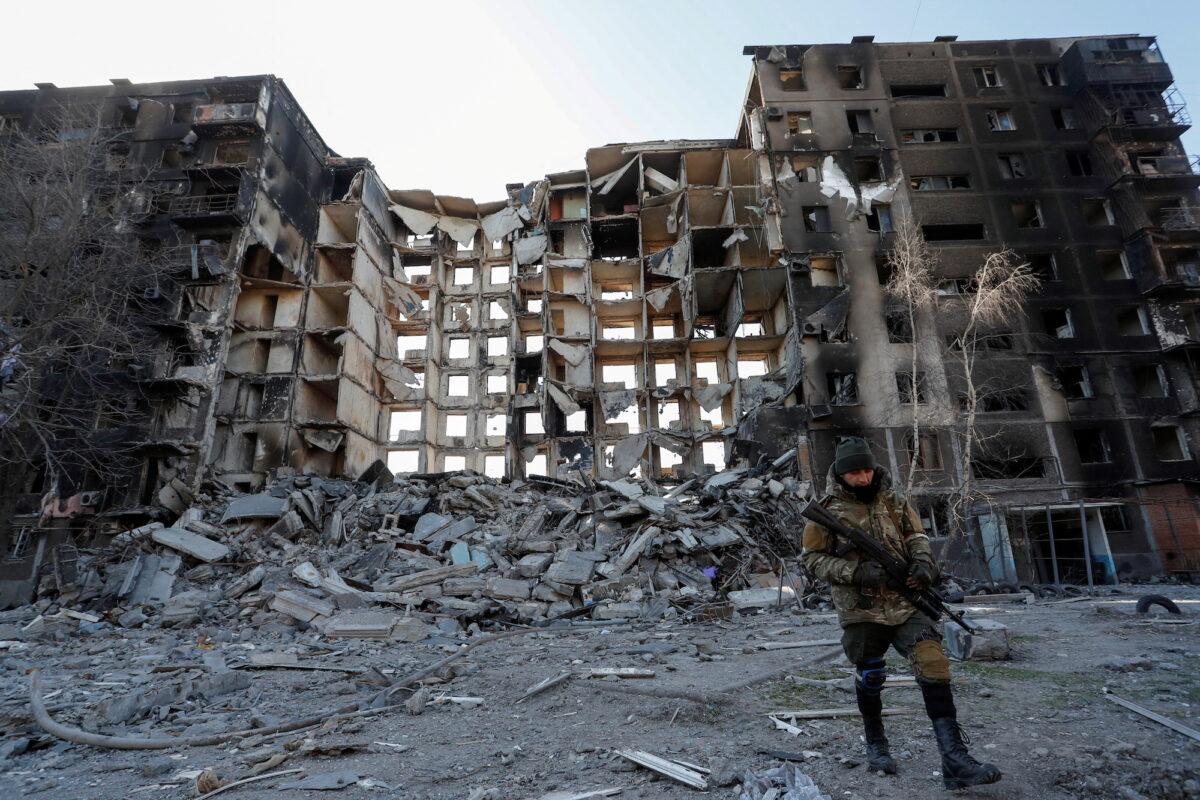 A service member of pro-Russian troops walks near an apartment building destroyed in the course of the Ukraine-Russia conflict in the besieged southern port city of Mariupol, Ukraine, on March 28, 2022. (Alexander Ermochenko/Reuters)
