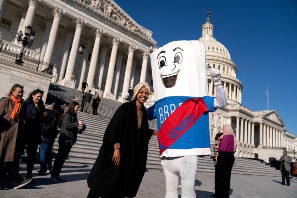 Rep. Ilhan Omar (D-Minn., left) stands with a climate activist dressed as the Build Back Better bill following a vote outside the U.S. Capitol in Washington on Nov. 19, 2021. President Joe Biden's signature plan to expand the social safety net and address climate change passed the House. (Stefani Reynolds/Bloomberg via Getty Images)