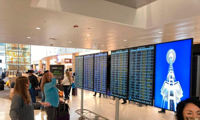 Travelers at Seattle-Tacoma International Airport check the status of flights, including a few that were canceled, on displays inside a gate terminal in Seattle, on April 1, 2022. (Ted S. Warren/AP Photo)