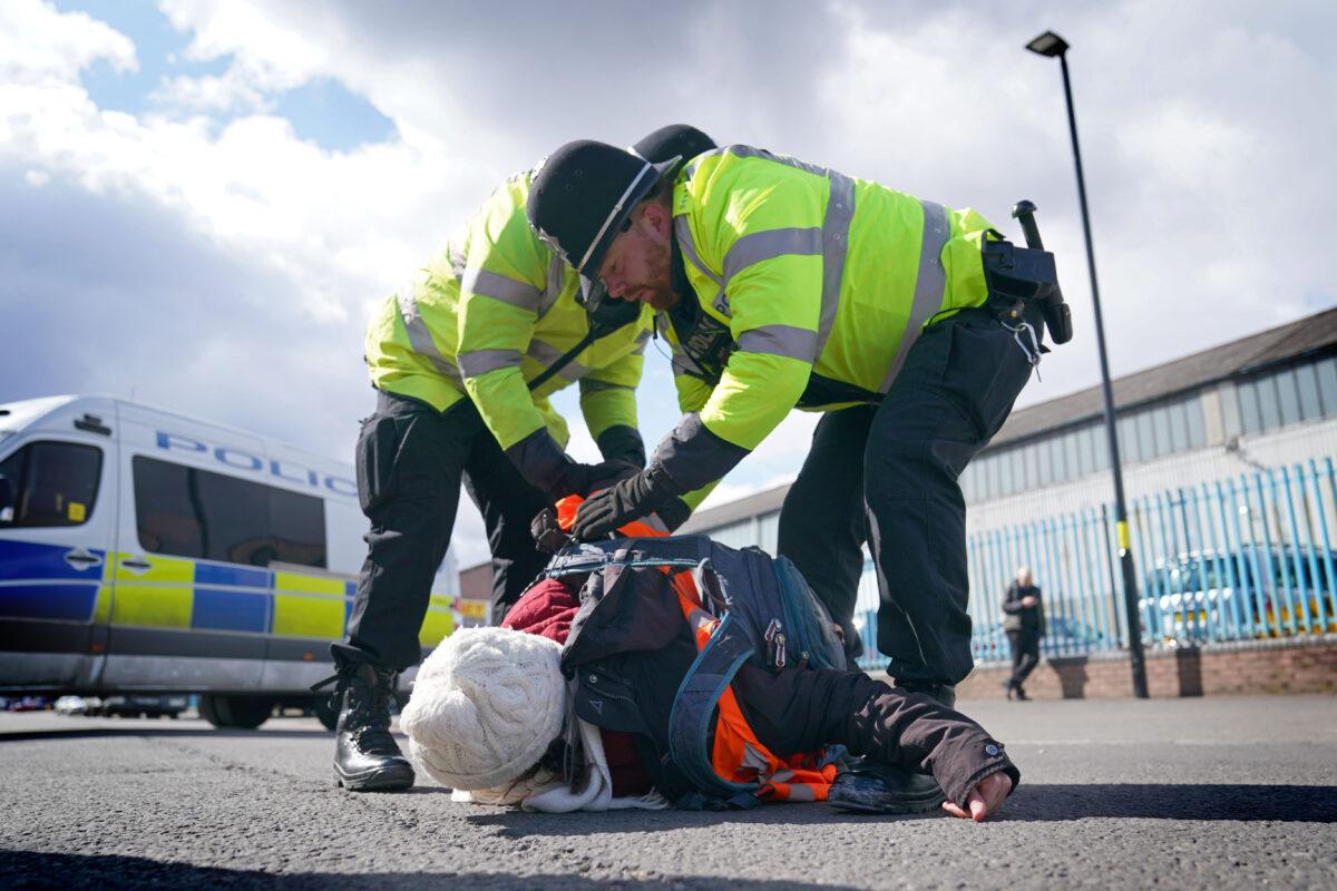 Police remove a Just Stop Oil activist taking part in a blockade of the ESSO Birmingham Fuel Terminal, in Birmingham, England, on April 1, 2022. (PA)