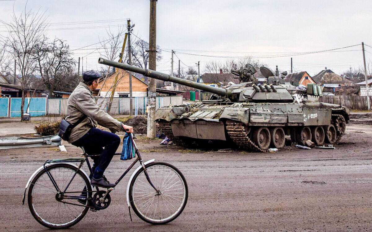 A man rides his bike past a destroyed Russian tank in Trostyanets, Ukraine, on March 30, 2022. (Chris McGrath/Getty Images)