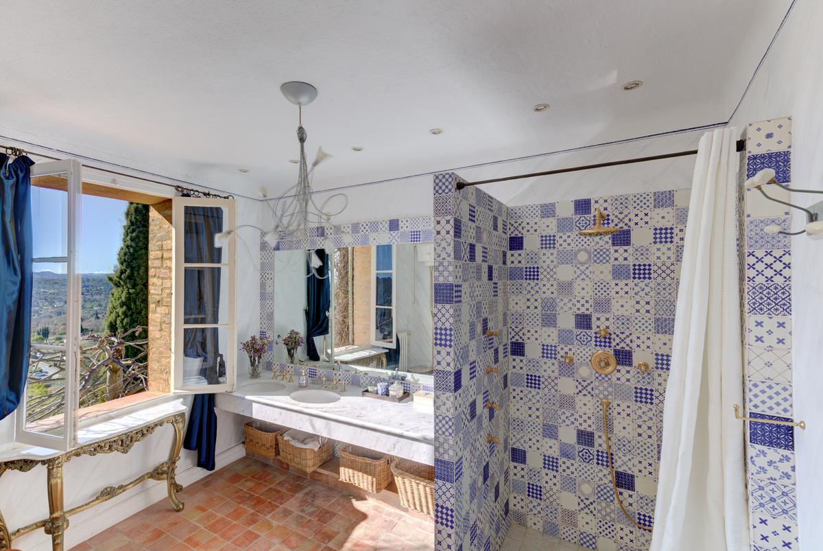 Here, one of the villa’s bathrooms looks out over the French countryside. A light and airy atmosphere is created with blue and white tiles and fixtures inside. (Courtesy of the villa owners & Carlton International)