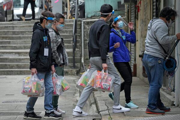 Workers deliver packages of coronavirus prevention materials to people during an anti-epidemic event in Hong Kong, on April 2, 2022. (Kin Cheung/AP Photo)