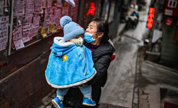 A woman wearing a face mask carries a baby in her arms in Wuhan in China's central Hubei province, on Jan. 22, 2021. (Hector Retamal/AFP via Getty Images)