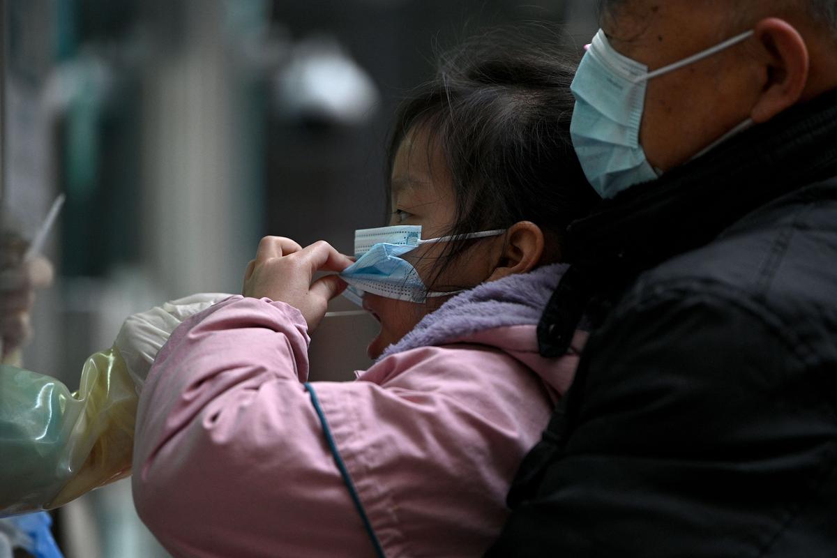 A health worker takes a swab sample on a girl to be tested for the COVID-19 coronavirus in Beijing on March 14, 2022, amid a record surge of infections across China. (Noel Celis/AFP via Getty Images)