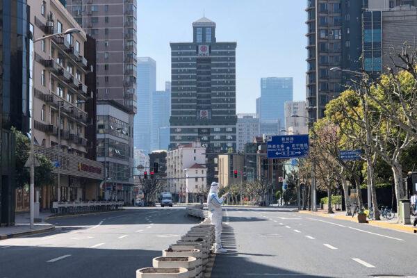 A worker in protective overalls stands in the middle of empty streets in a lockdown area in the Jingan district of western Shanghai on April 4, 2022. (Chen Si/AP Photo)