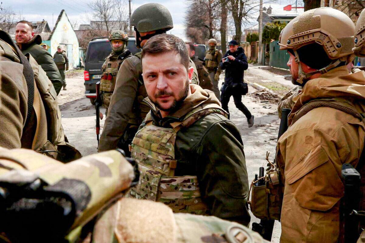Ukraine's President Volodymyr Zelenskyy looks on as he is surrounded by Ukrainian servicemen in Bucha, outside Kyiv, Ukraine, on April 4, 2022. (Marko Djurica/Reuters)