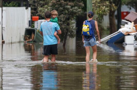 A man carries a child through floodwaters in Vincent Street, Auchenflower in Brisbane, Australia, on March 3, 2022 (Peter Wallis/Getty Images)