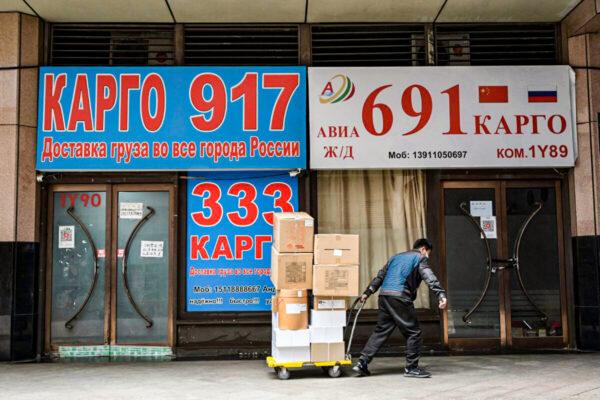 A delivery man hauls packages past stores advertising international logistics transportation to Russia, at Ritan International Trade Center in Beijing on March 22, 2022. (Jade Gao/AFP via Getty Images)