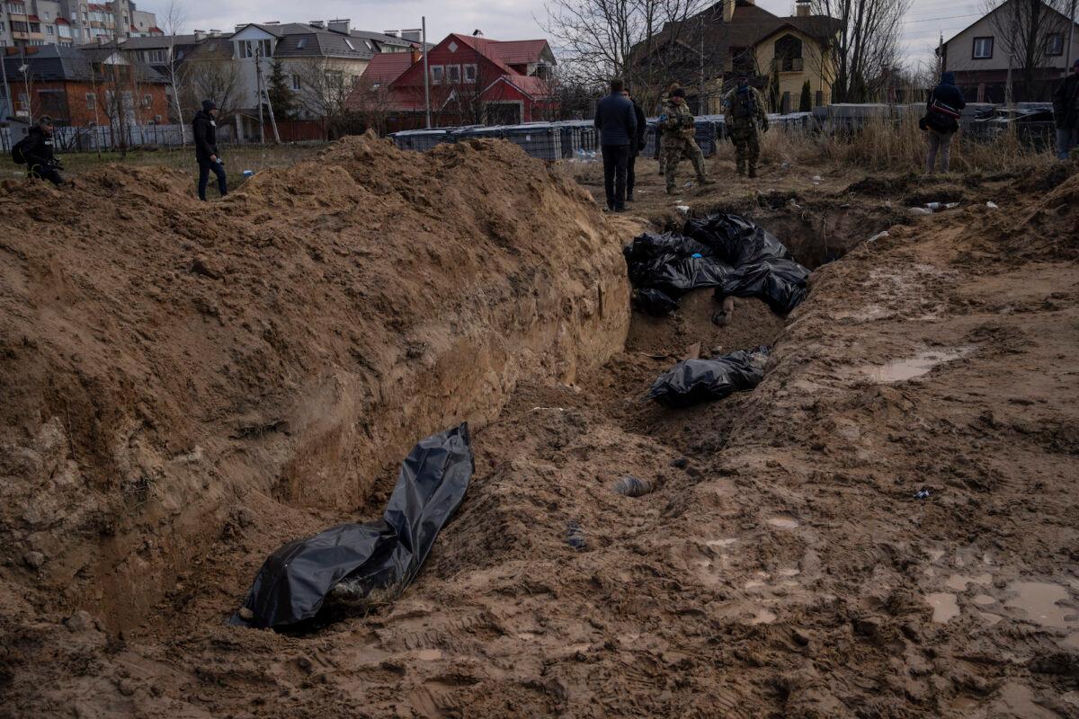 Journalists work next to a mass grave in Bucha, on the outskirts of Kyiv, Ukraine, on April 4, 2022. (Rodrigo Abd/AP Photo)