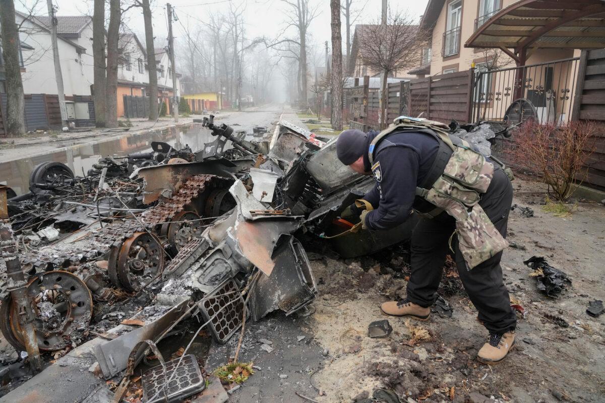 A Ukrainian soldier checks a destroyed Russian tank in Irpin close to Kyiv, Ukraine, on April 1, 2022. (Efrem Lukatsky/AP Photo)