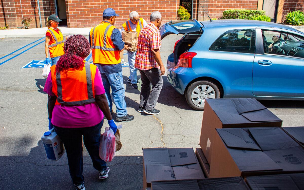 Volunteers at Friendship Baptist Church food pantry assist cars in front of the food ministry building area in Yorba Linda, Calif., on April 5, 2022. (John Fredricks/The Epoch Times)