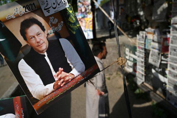 A resident stands beside a picture of Pakistan's then Prime Minister Imran Khan as he looks at the morning newspapers displayed for sale at a roadside stall in Islamabad on April 4, 2022. (Aamir Qureshi/AFP via Getty Images)