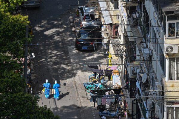 Health workers wearing personal protective equipment walk on a street in a neighborhood during a COVID-19 lockdown in the Jing'an district in Shanghai on April 8, 2022. (Hector Retamal/AFP via Getty Images)