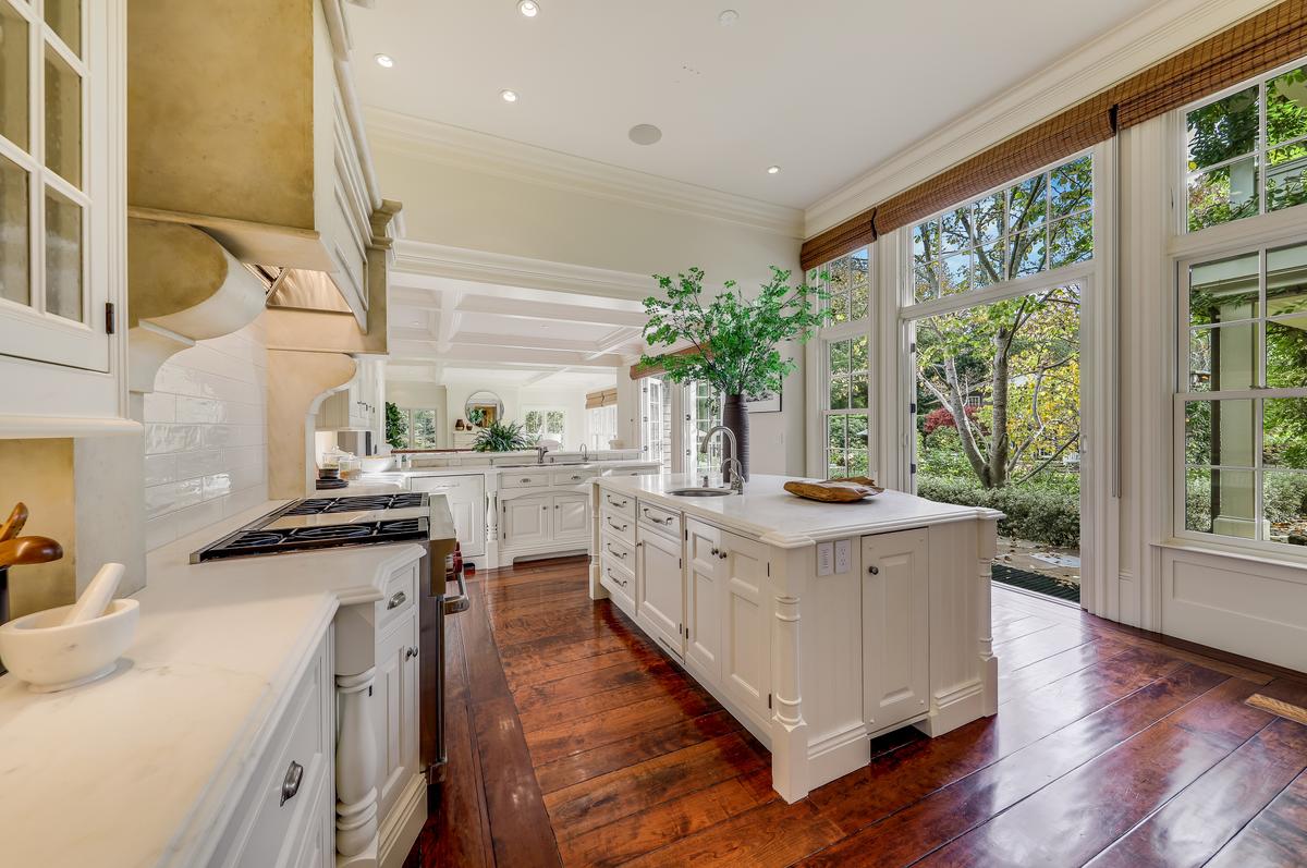 The well-appointed kitchen features Calacatta marble slabs, a bar/counter with seating, two sinks, a water filtration system, professional-grade appliances, a huge walk-in pantry with a desk, a large breakfast space, and two sets of glass doors that open to the patio, pool, and exterior living spaces. (Courtesy of Jason Wells Photography and Golden Gate Creative/Tracy McLaughlin)