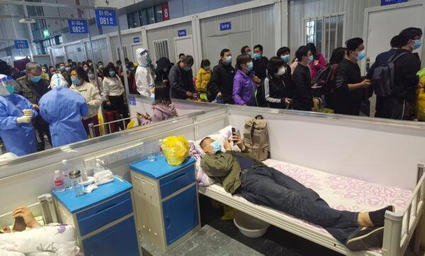 People who have been negative in the last two nucleic acid tests line up to leave a temporary hospital converted from the National Exhibition and Convention Center to quarantine COVID-positive people in Shanghai on April 18, 2022. (Chinatopix via AP)