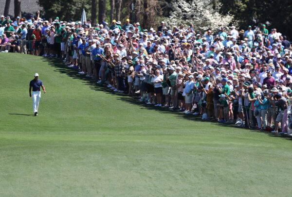  The giant gallery of patrons following five-time Masters champion Tiger Woods applaude as he walks down the first fairway after teeing off to begin his practice round for the Masters at Augusta National Golf Club in Augusta, Ga., on April 4, 2022. (Curtis Compton/Atlanta Journal-Constitution via AP)