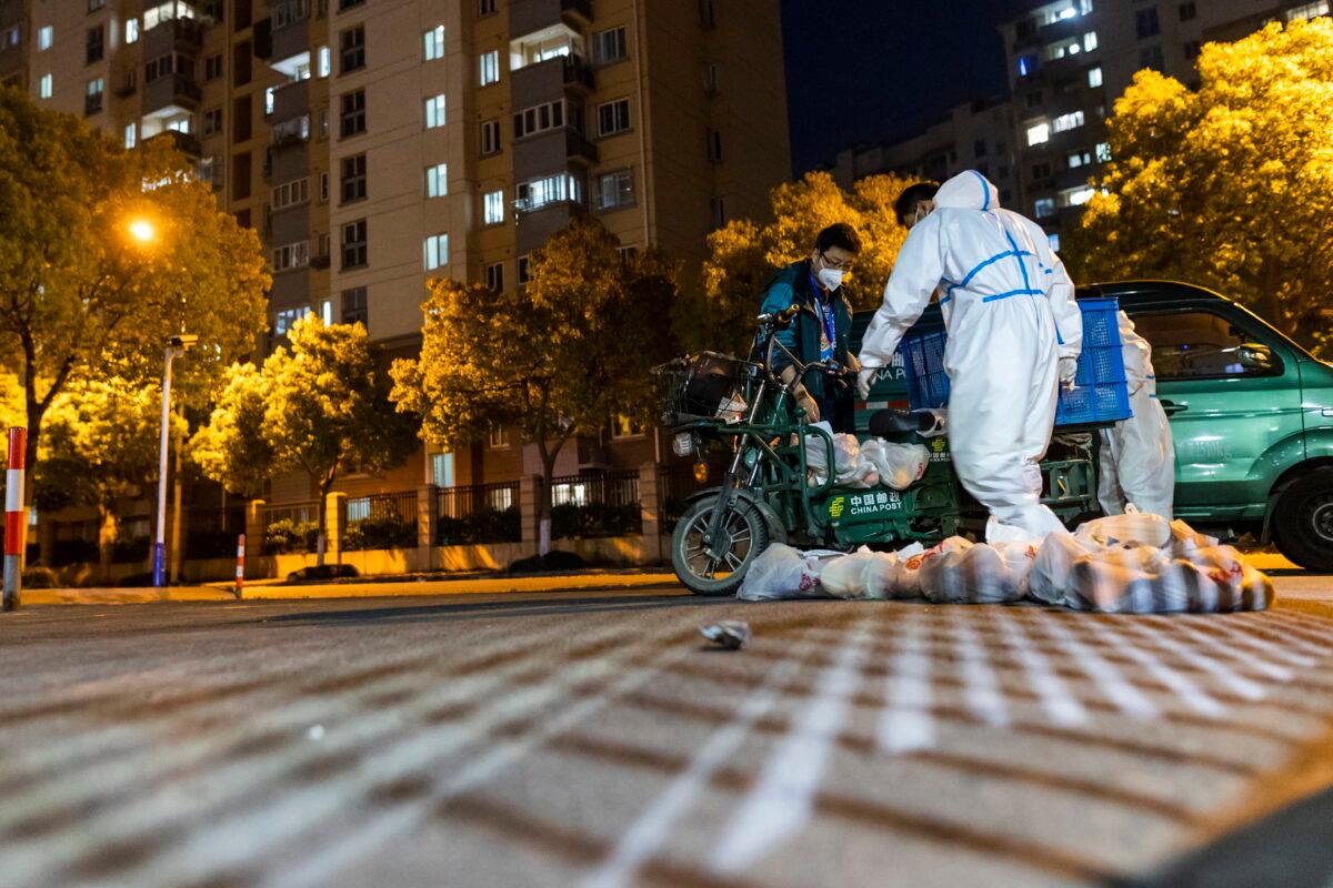 Deliverymen wearing protective suits carry bags of food at the gate of a residential community in Shanghai, China, on April 11, 2022. Many residents in the city of 26 million have been confined to their homes for up to three weeks as China maintains its "zero-COVID" strategy of handling outbreaks with strict isolation and mass testing. (AP Photo)