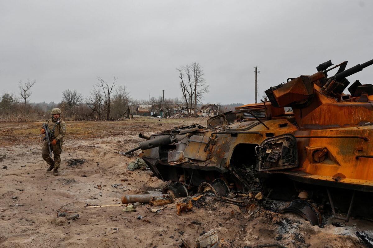 A Ukrainian service member inspects a destroyed Russian BTR-82 armored personal carrier (APC) in a village near a frontline near Kyiv, Ukraine, on March 31, 2022. (Serhii Nuzhnenko/Reuters)